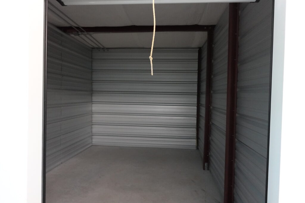 Inside our Climate Controlled Self Storage Unit with 24/7 Access - Photo depicts empty clean and well lit storage unit with white walls.