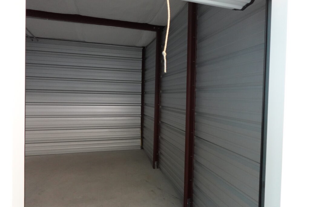 Inside our Climate Controlled Self Storage Unit with 24/7 Access - Photo depicts empty clean and well lit storage unit with white walls.